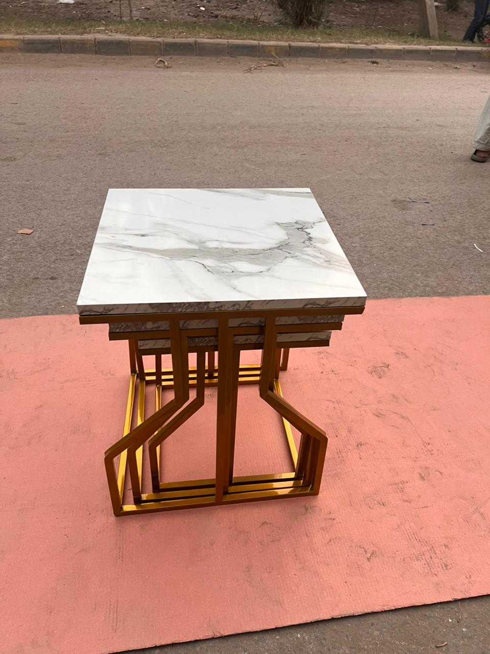 Contemporary nesting tables with golden metal frames and marble-texture tops, ideal for modern metal furniture decor.