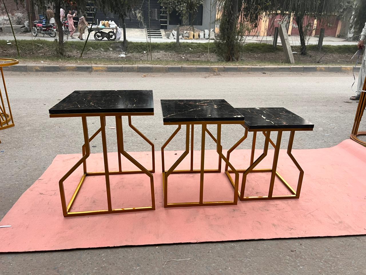 Contemporary nesting tables with golden metal frames and marble-textured tops, modern metal furniture for living space decor.