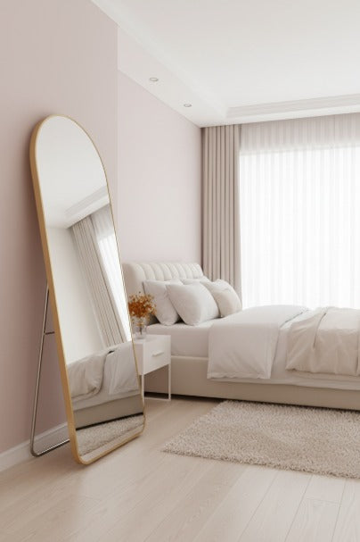 Modern bedroom with a large floor mirror, bed, and side table.