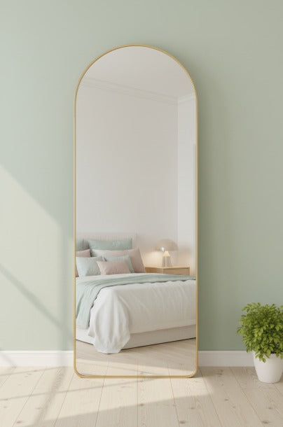 Full-length mirror leaning against a light green wall in a bedroom.